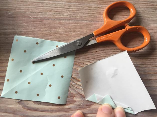 Paper and a pair of scissors and a hand folding paper